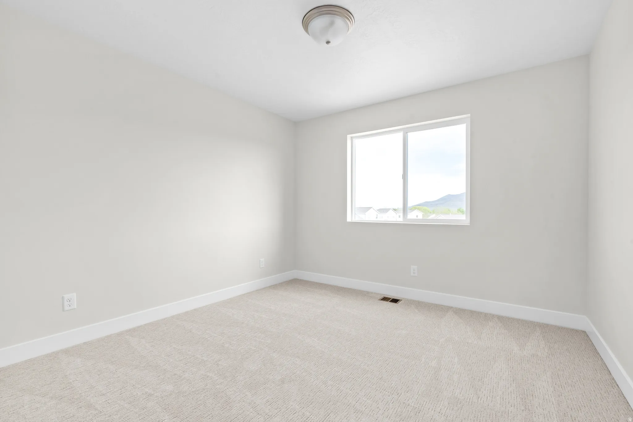 Spare room with baseboards and light colored carpet