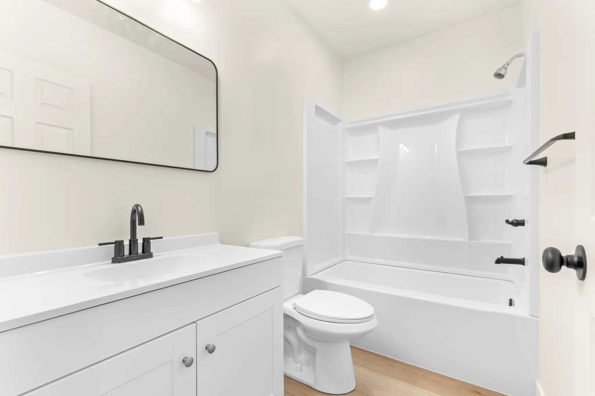 Bathroom featuring vanity, light wood finished floors, tub / shower combination, and recessed lighting