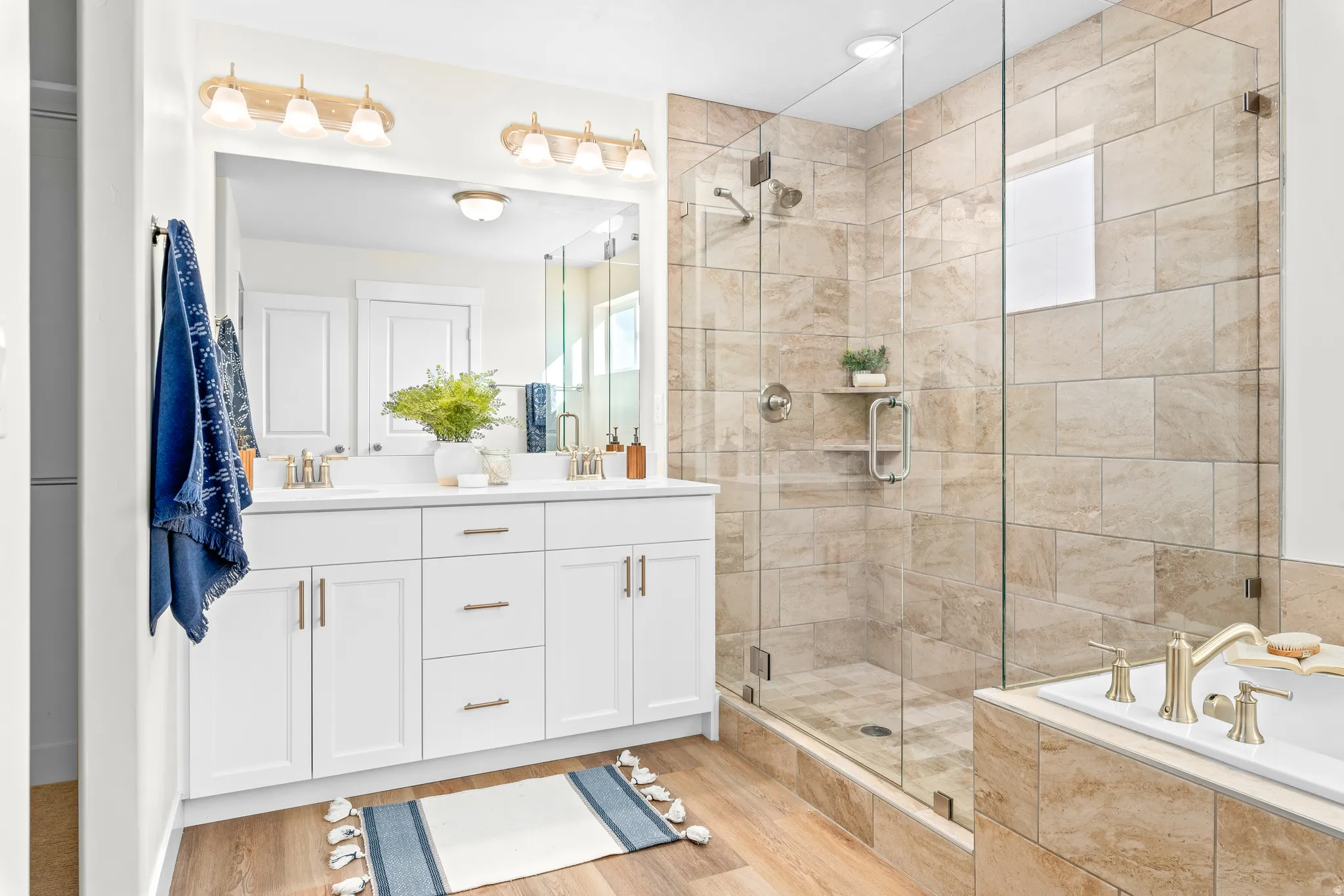 Bathroom with double vanity, a bath, a shower stall, and light wood-type flooring