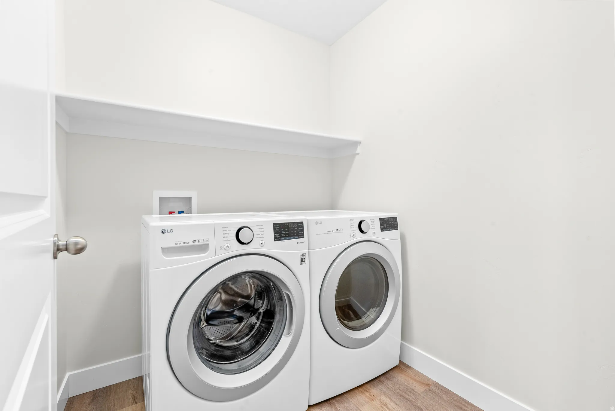 Laundry room with light wood finished floors and washing machine and clothes dryer
