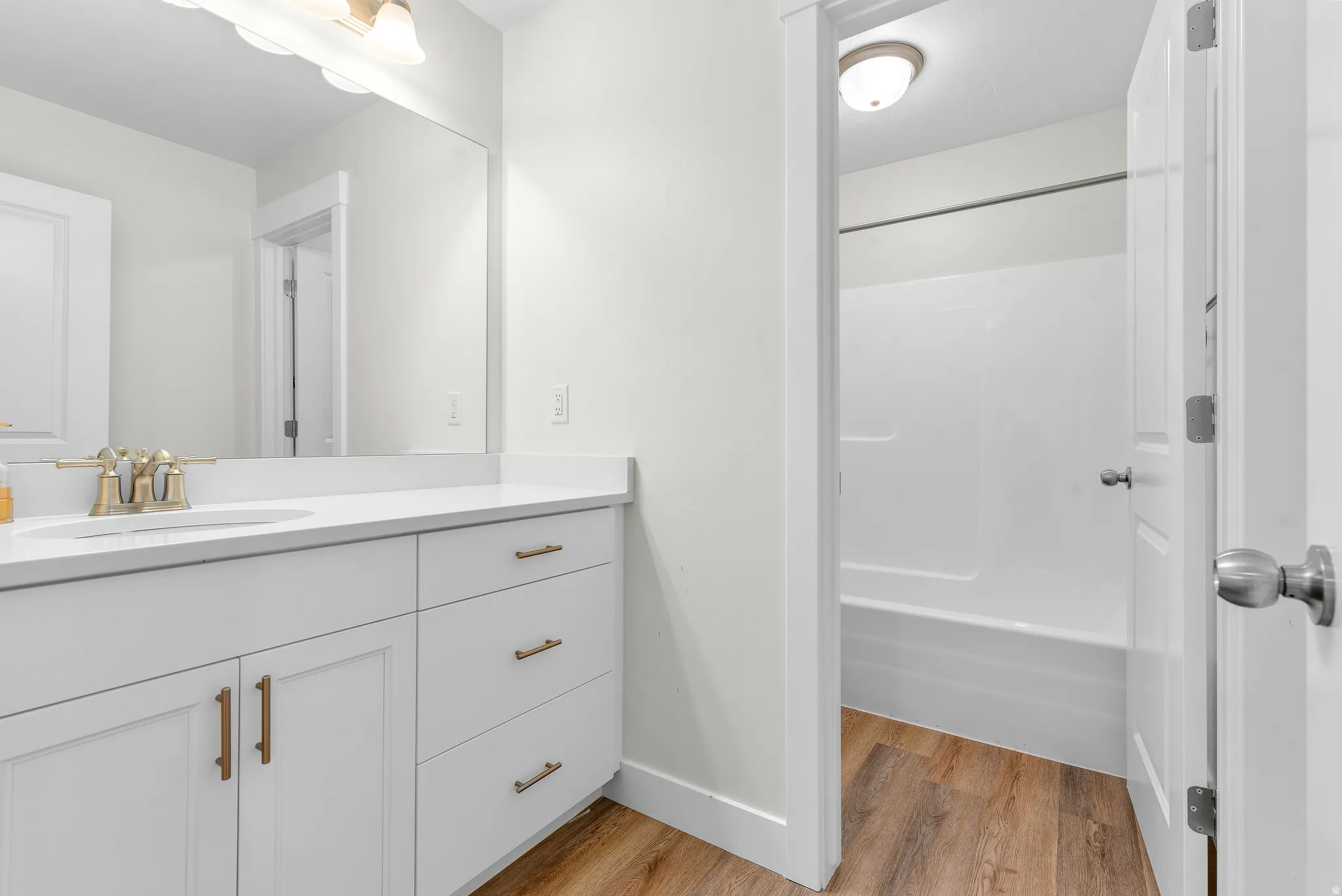 Full bathroom featuring vanity, light wood-style flooring, and shower / washtub combination