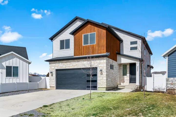 Modern home with stone siding, driveway, and a garage