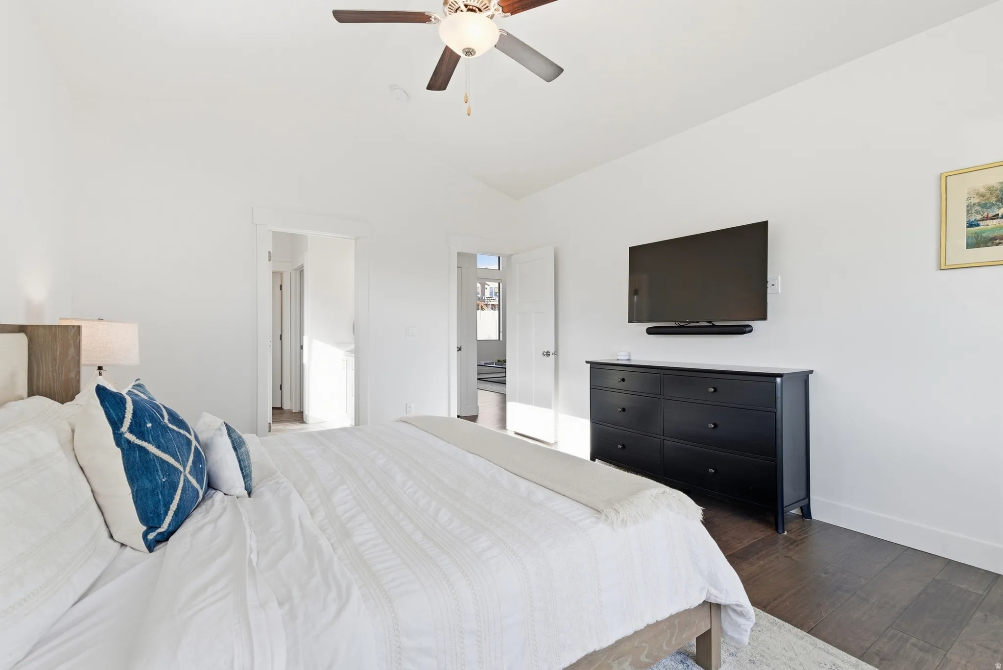 Bedroom with dark wood-style floors, a ceiling fan, and lofted ceiling