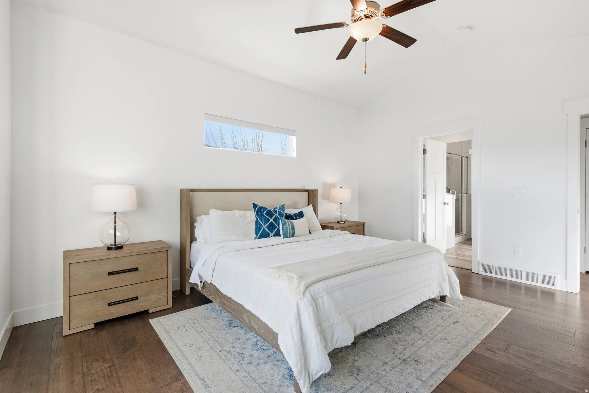 Bedroom with dark wood finished floors, lofted ceiling, ceiling fan, and ensuite bathroom