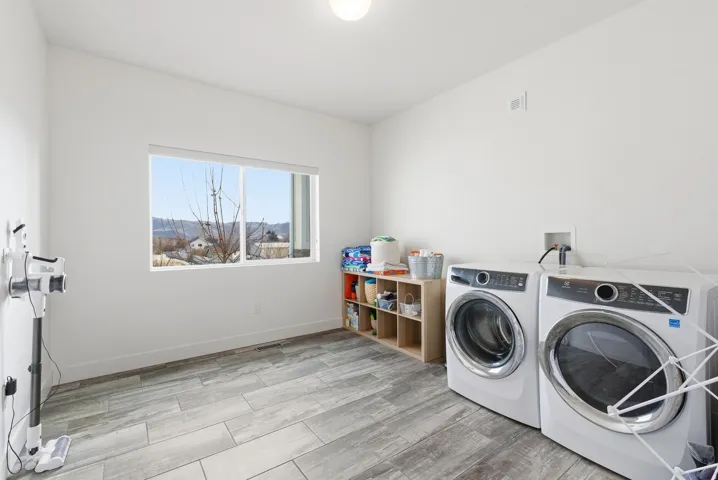 Laundry area with wood finish floors and washing machine and clothes dryer