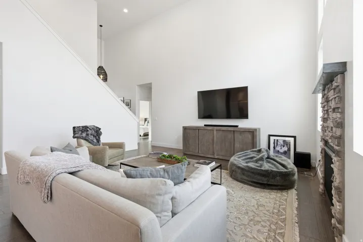 Living area featuring wood-type flooring, a high ceiling, and a stone fireplace