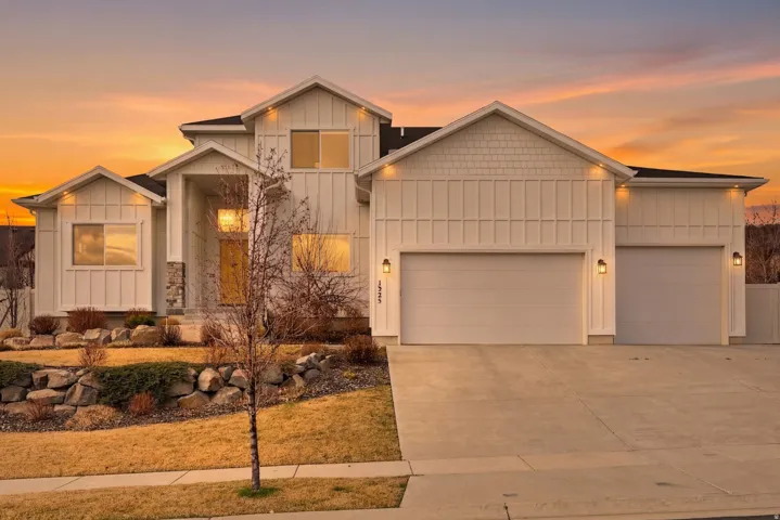 View of front of home with board and batten siding, an attached garage, and driveway