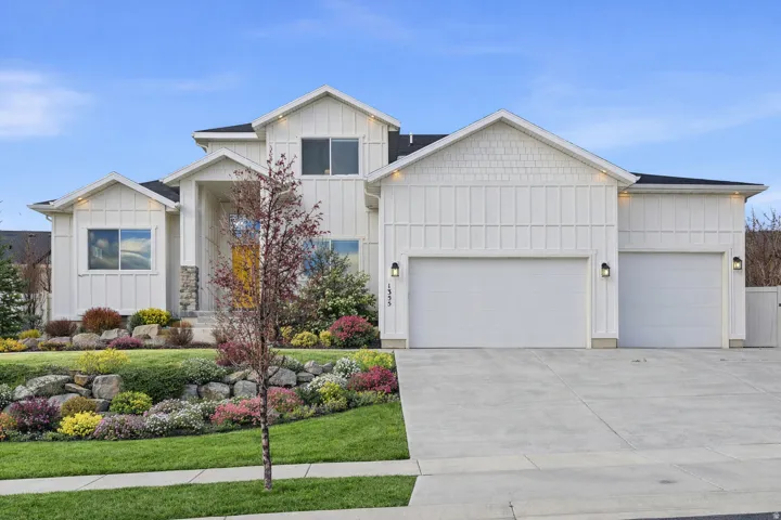 Modern inspired farmhouse with board and batten siding, an attached garage, concrete driveway, and a front yard