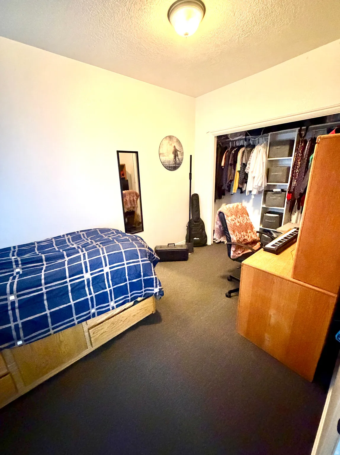 Bedroom with dark carpet, a closet, and a textured ceiling