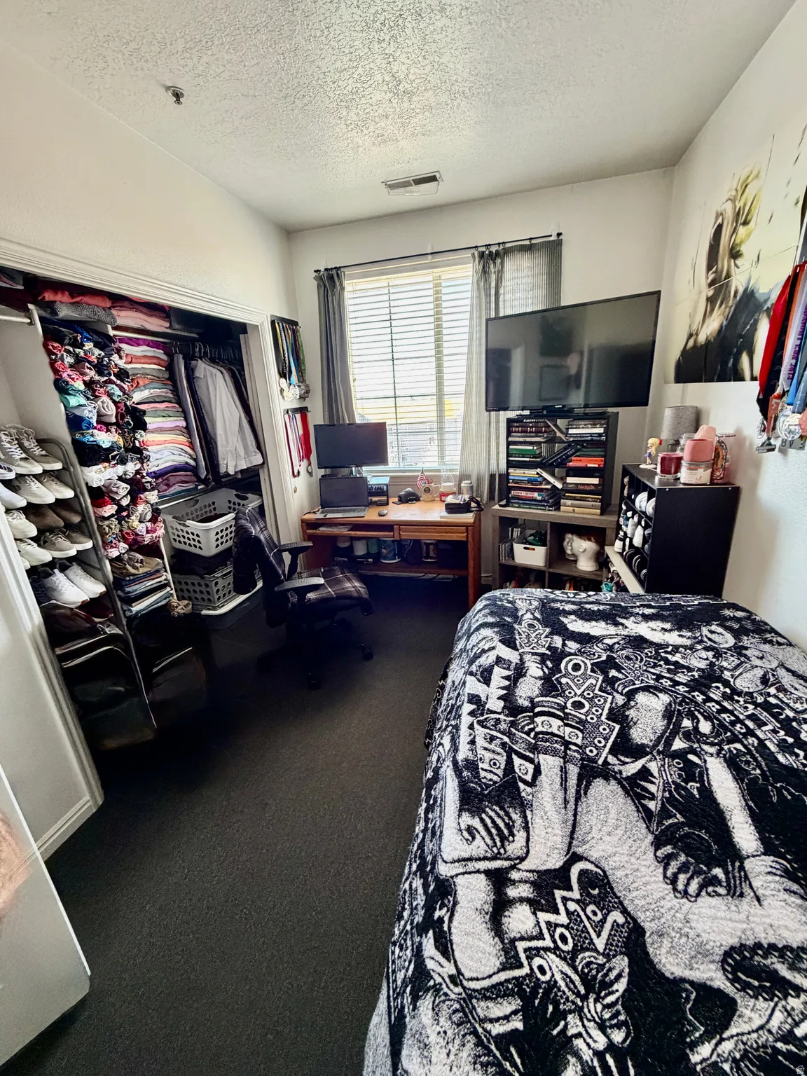 Bedroom with dark carpet, a textured ceiling, and a closet