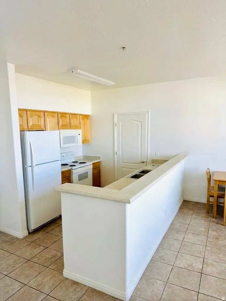 Kitchen with white appliances, light countertops, light tile patterned floors, and a textured ceiling