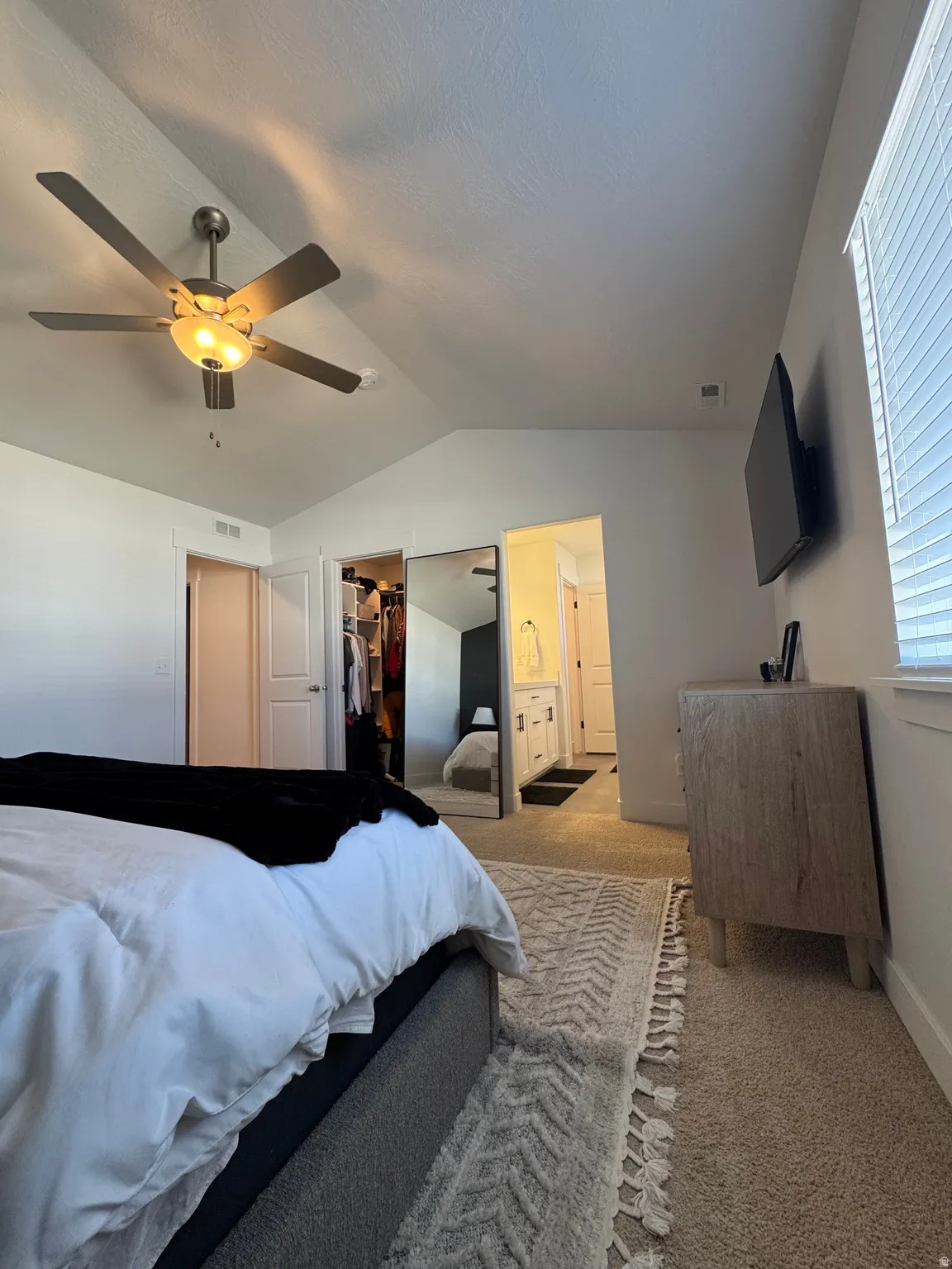 Carpeted bedroom with ceiling fan, ensuite bath, and a walk in closet