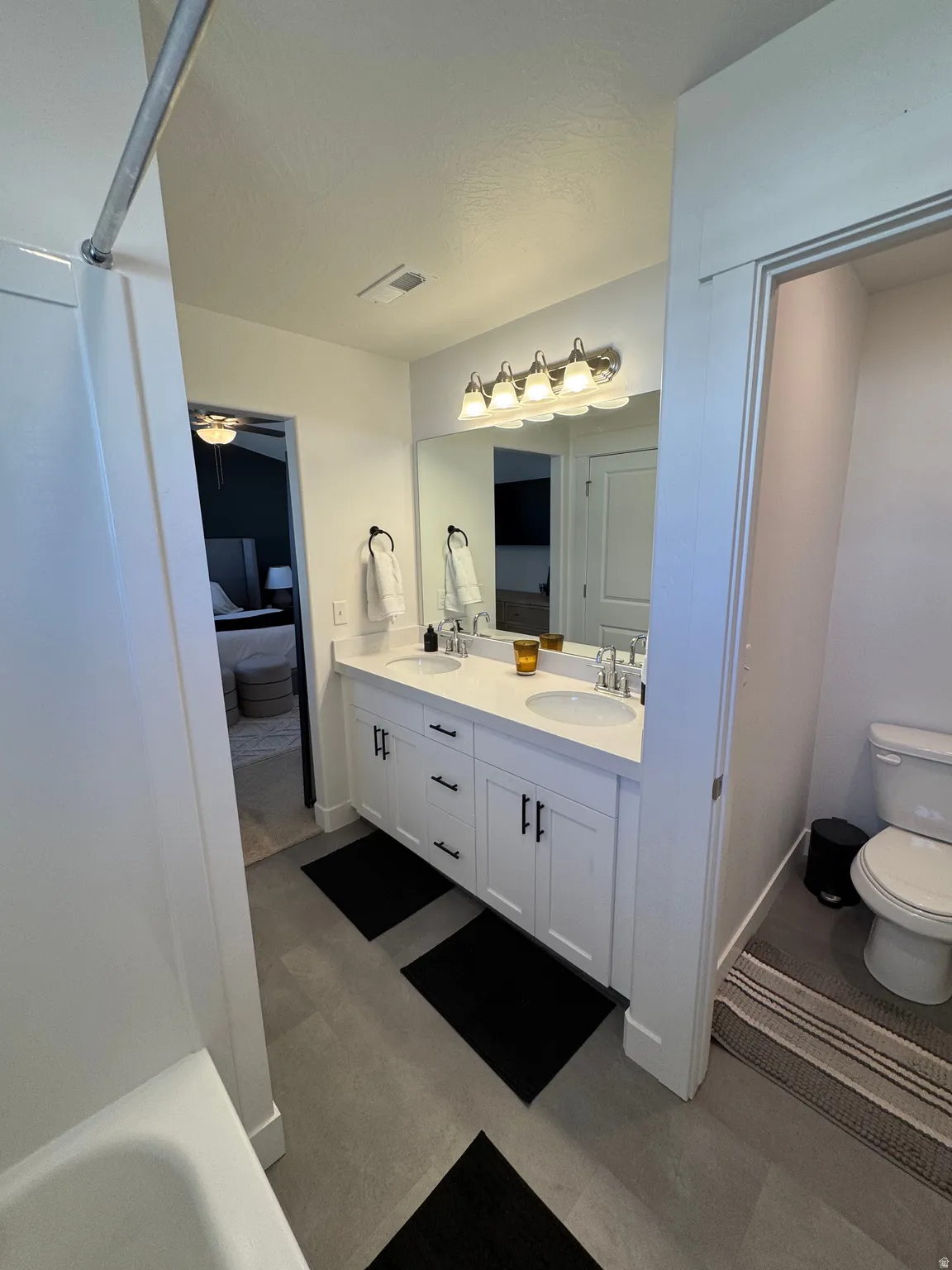 Ensuite bathroom with double vanity, a bath, and dark floors