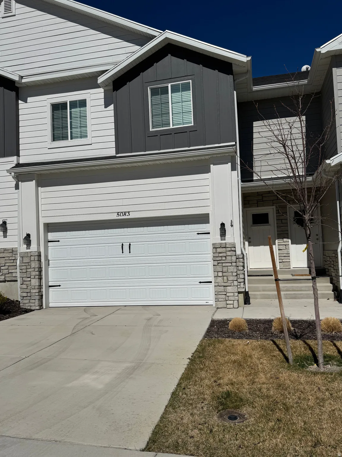 View of front of house featuring stone siding, board and batten siding, driveway, and a garage