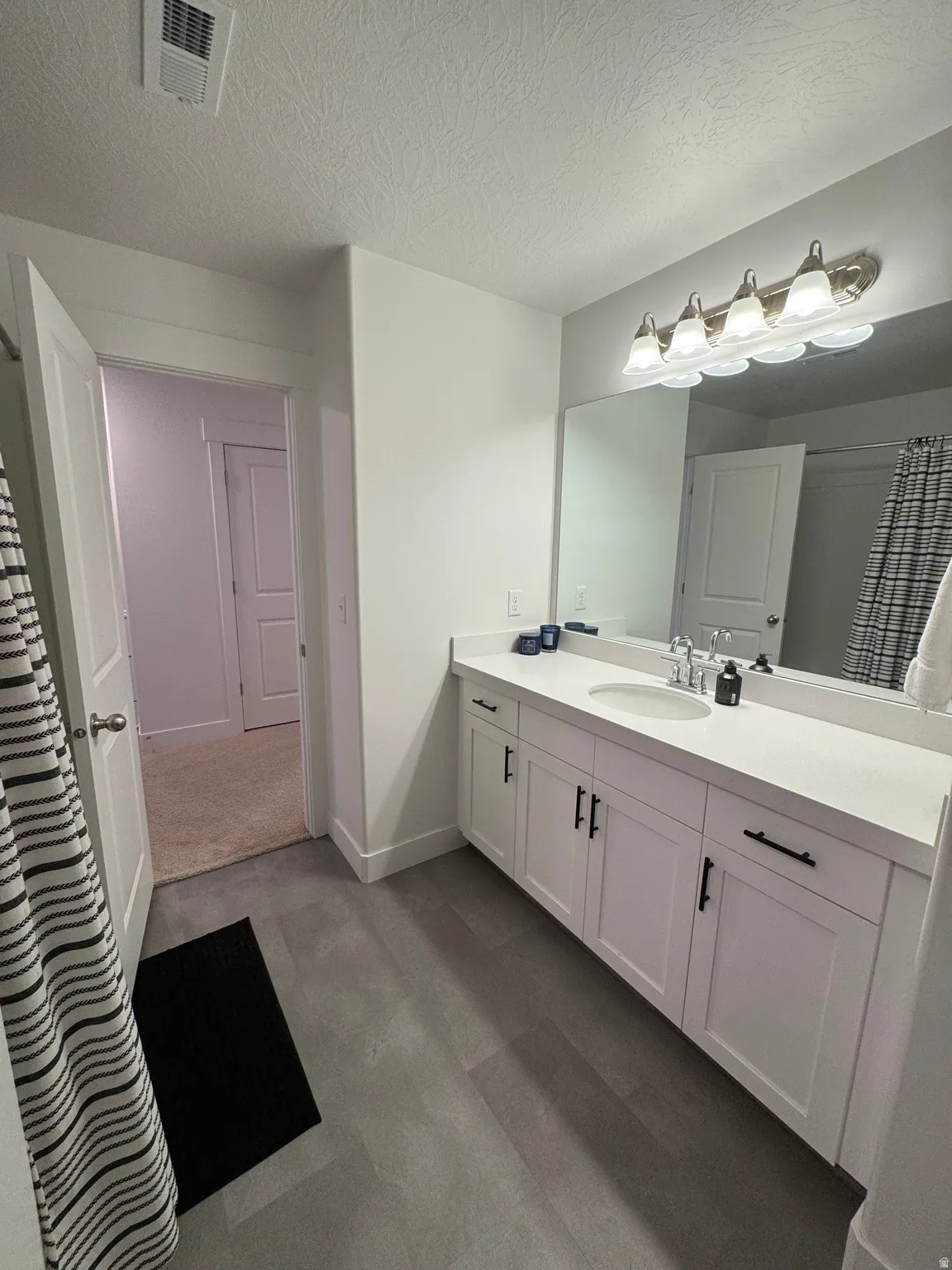 Full bathroom featuring a shower with curtain, vanity, and a textured ceiling
