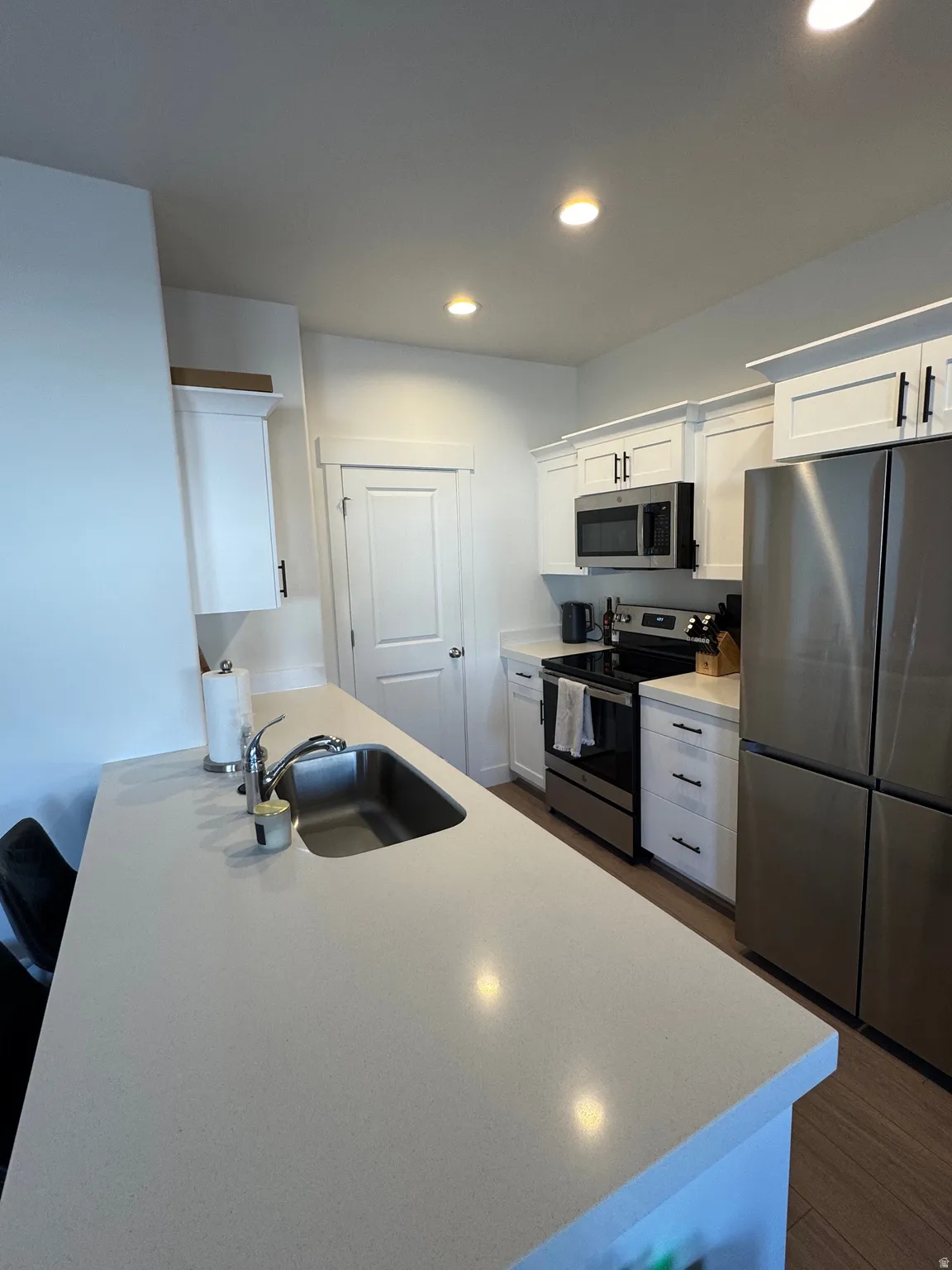Kitchen with white cabinetry, stainless steel appliances, recessed lighting, dark wood-type flooring, and a peninsula