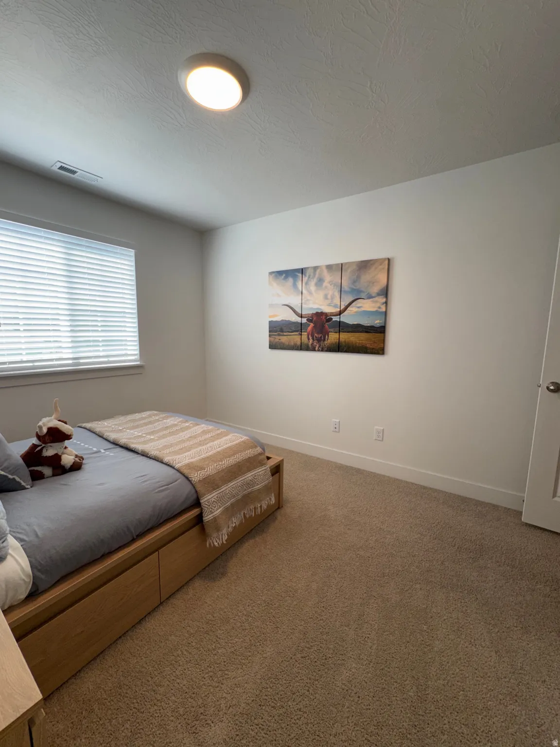 Carpeted bedroom featuring baseboards and a textured ceiling