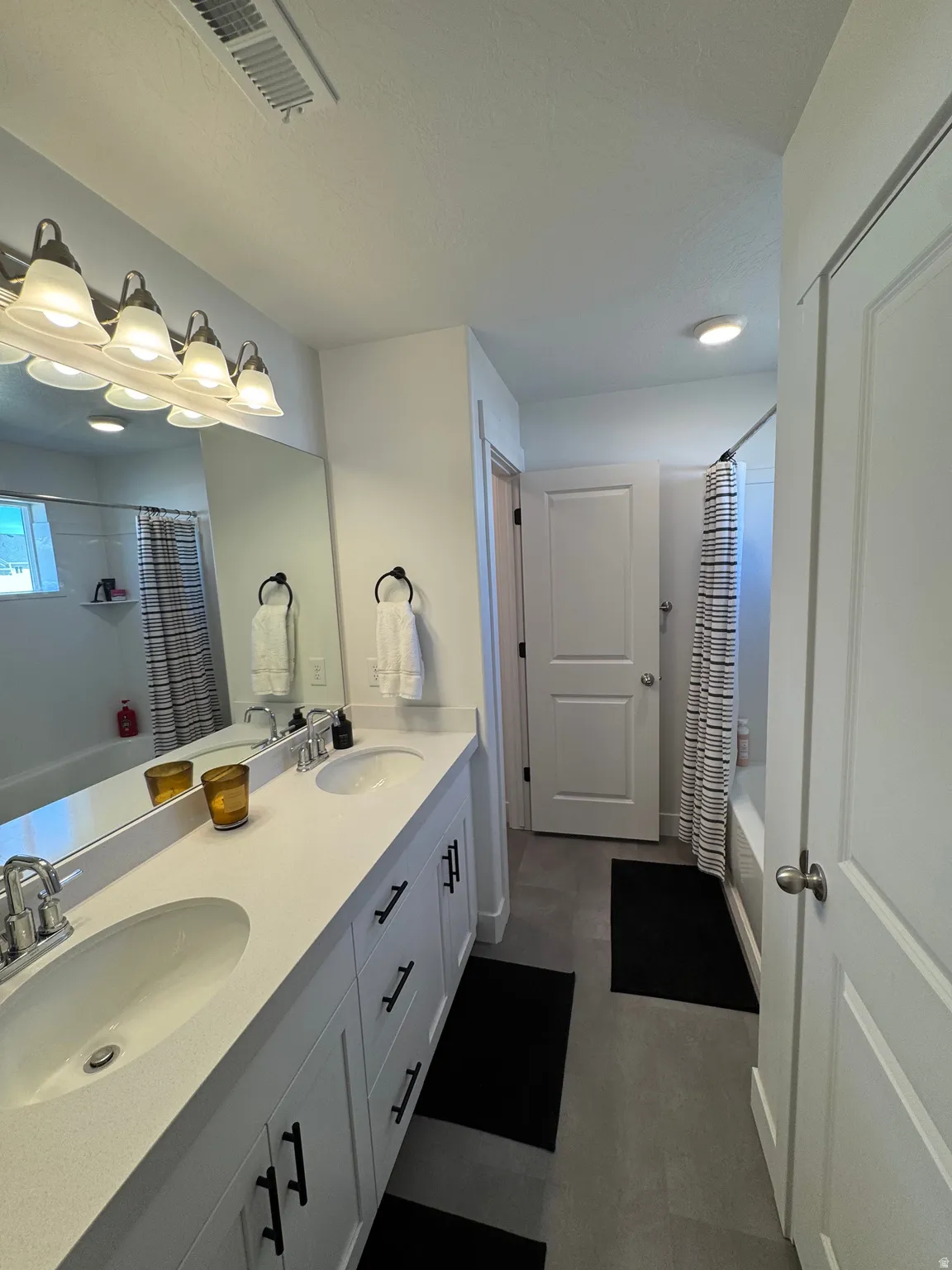 Bathroom with double vanity and shower / bath combination with curtain