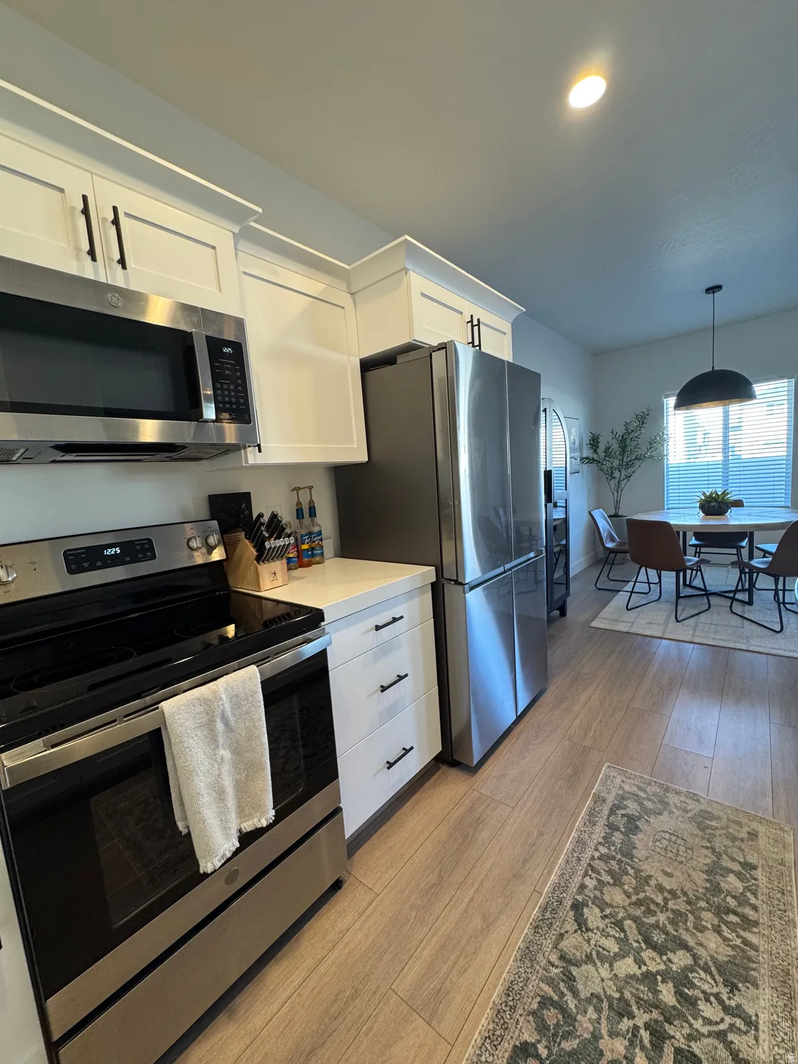 Kitchen with stainless steel appliances, white cabinetry, light countertops, and light wood finished floors