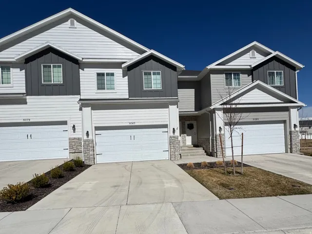 View of front of house featuring board and batten siding, stone siding, an attached garage, and driveway