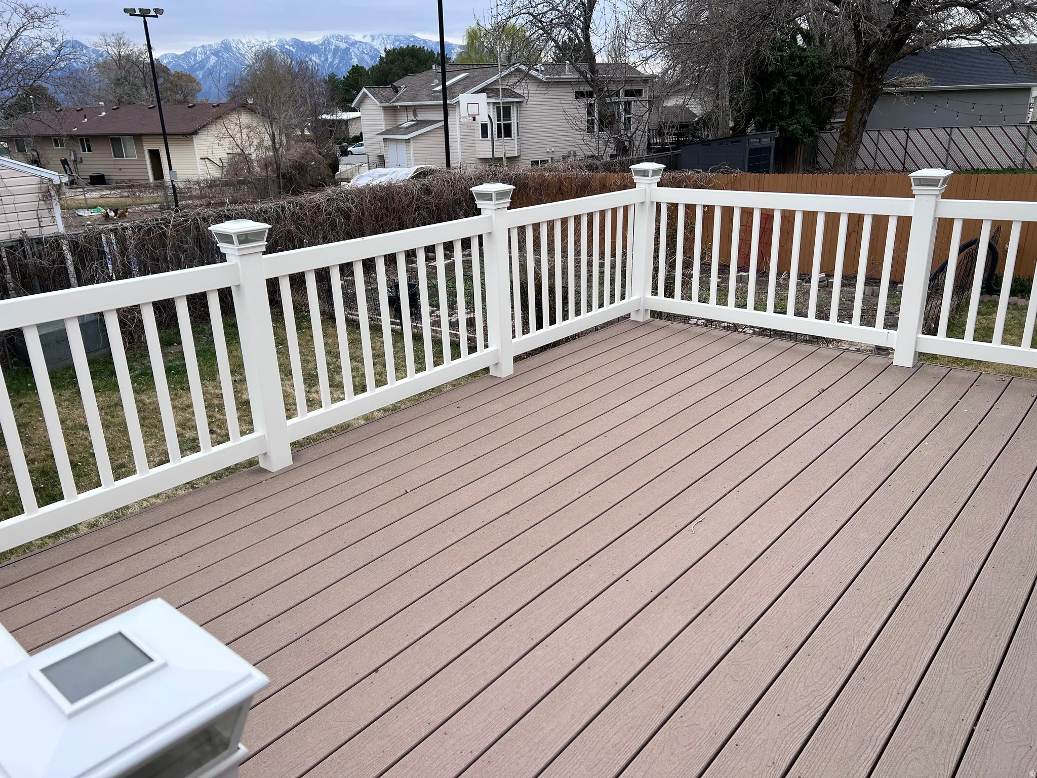 Wooden terrace featuring a fenced backyard, a residential view, and a mountain view
