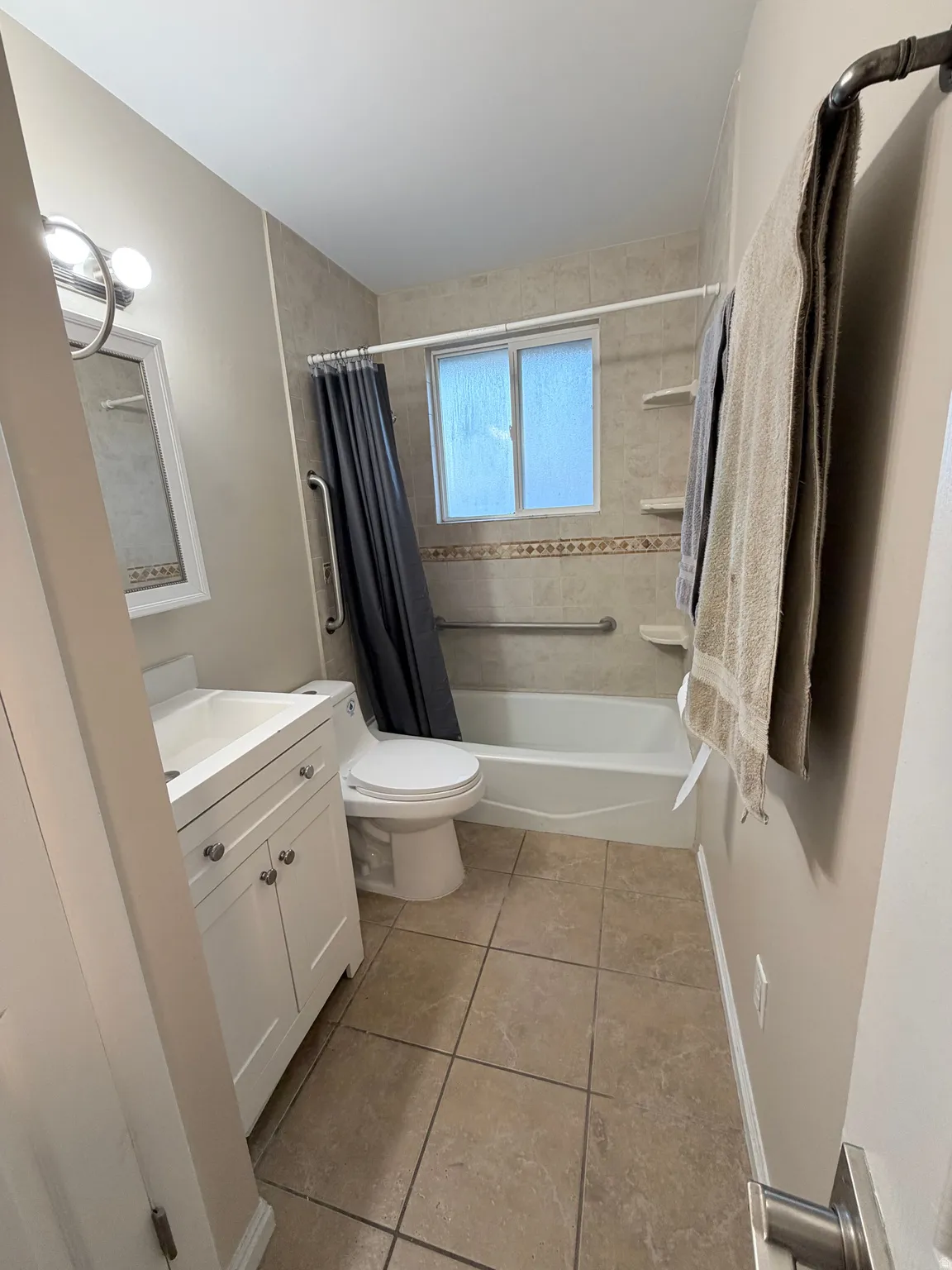 Bathroom featuring vanity, shower / bathtub combination with curtain, and light tile patterned floors