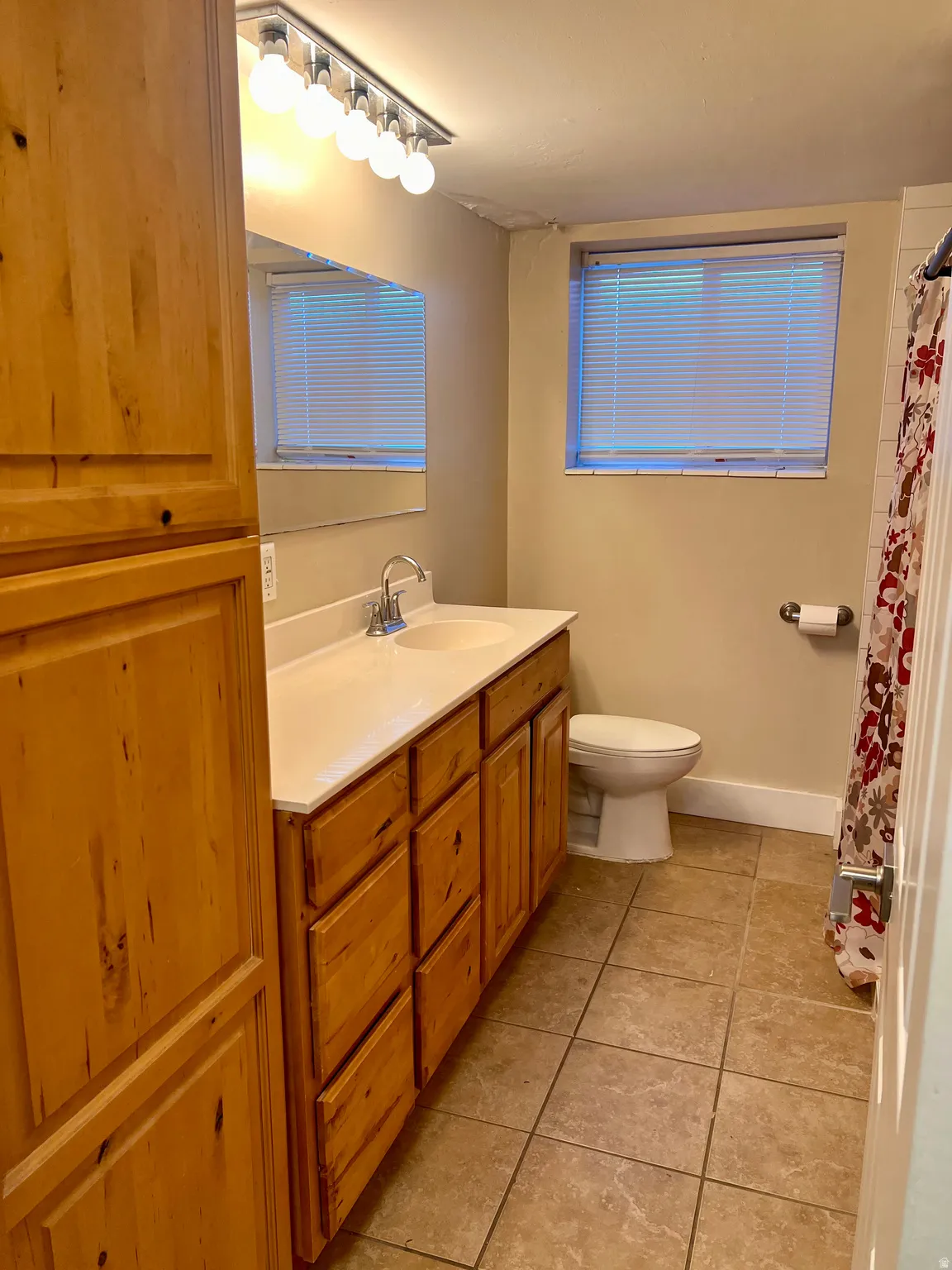 Full bath featuring vanity, light tile patterned flooring, and a shower with curtain