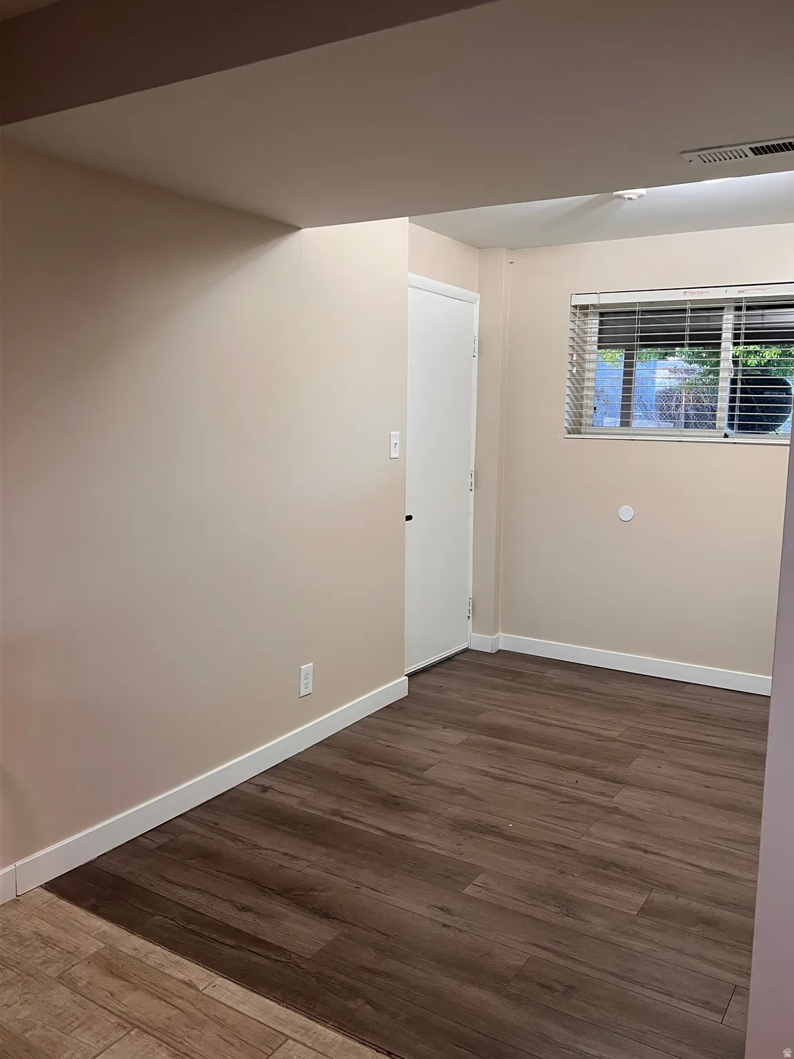 Empty room featuring dark wood finished floors and baseboards