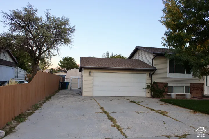 Exterior featuring horizontal siding, brick masonry detailing, two-car garage, concrete driveway, and detached storage shed