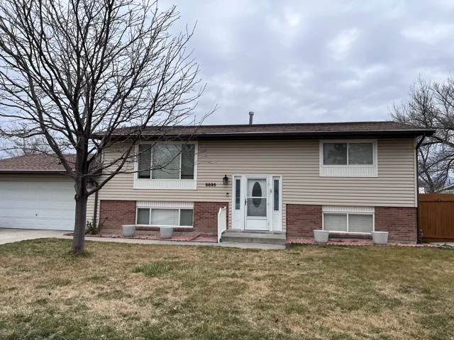 Bi-level home featuring a front yard, brick siding, a garage, and driveway