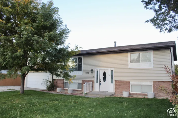 Split-level exterior featuring horizontal siding, brick masonry, an attached two-car garage, and a central entry with sidelights
