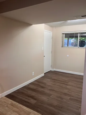 Empty room featuring dark wood finished floors and baseboards