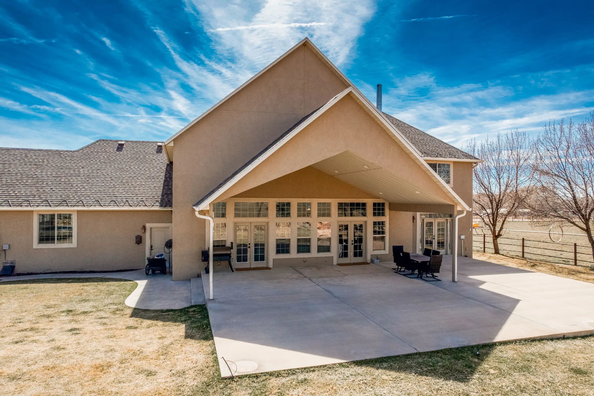 Rear view of house featuring french doors, stucco siding, a patio area, and roof with shingles