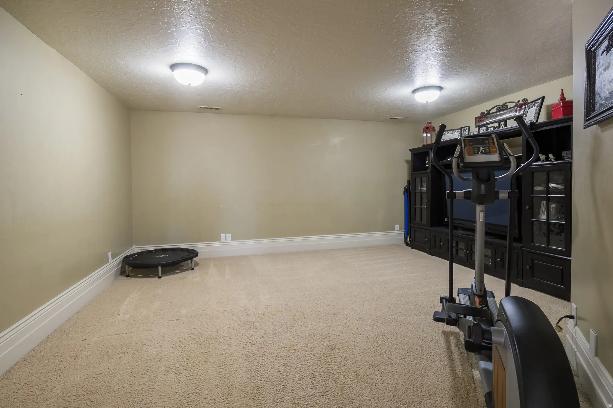 Workout room featuring a textured ceiling and light carpet