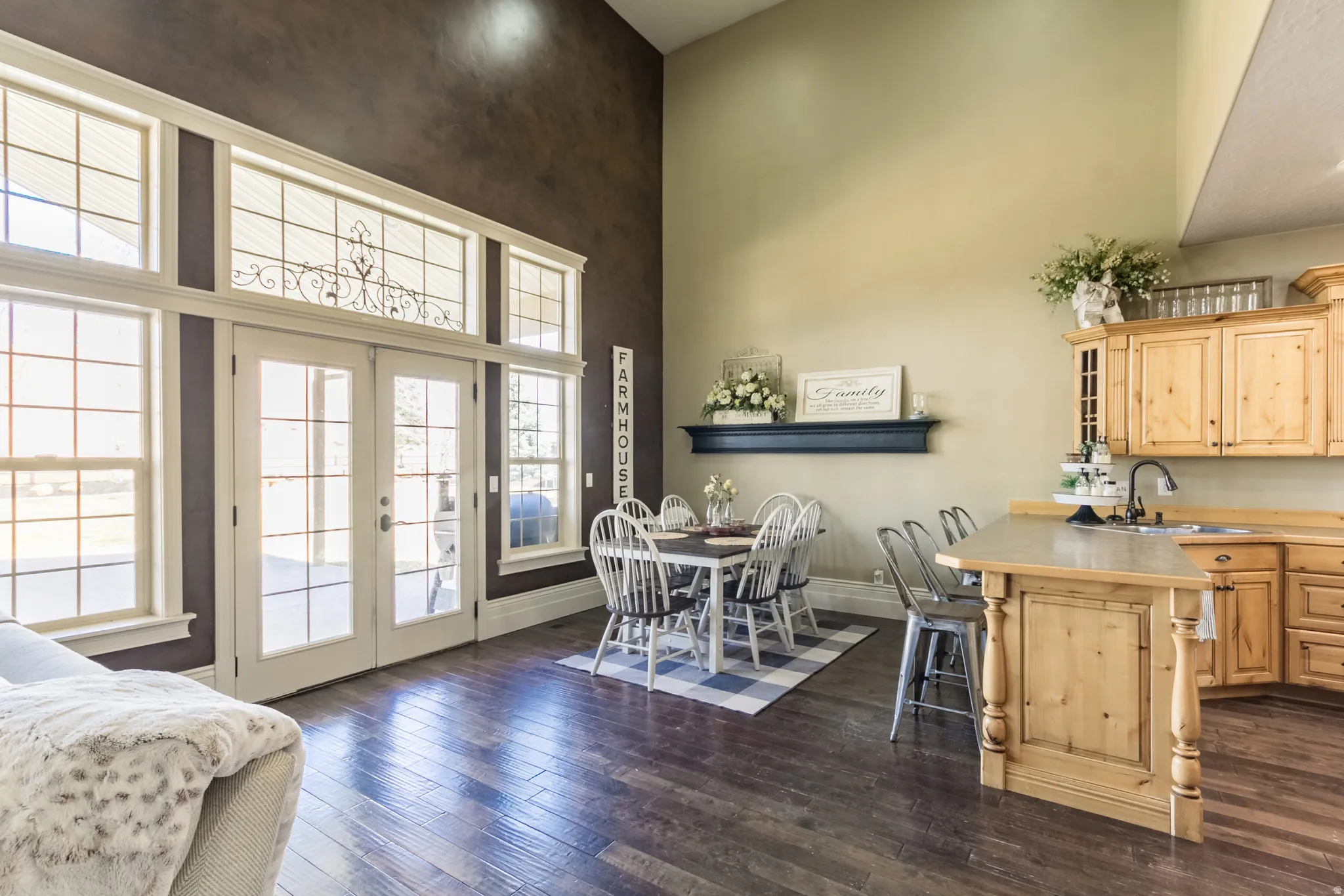 Kitchen with light wood finish cabinetry, a peninsula, dark wood-style floors, light countertops, and a high ceiling