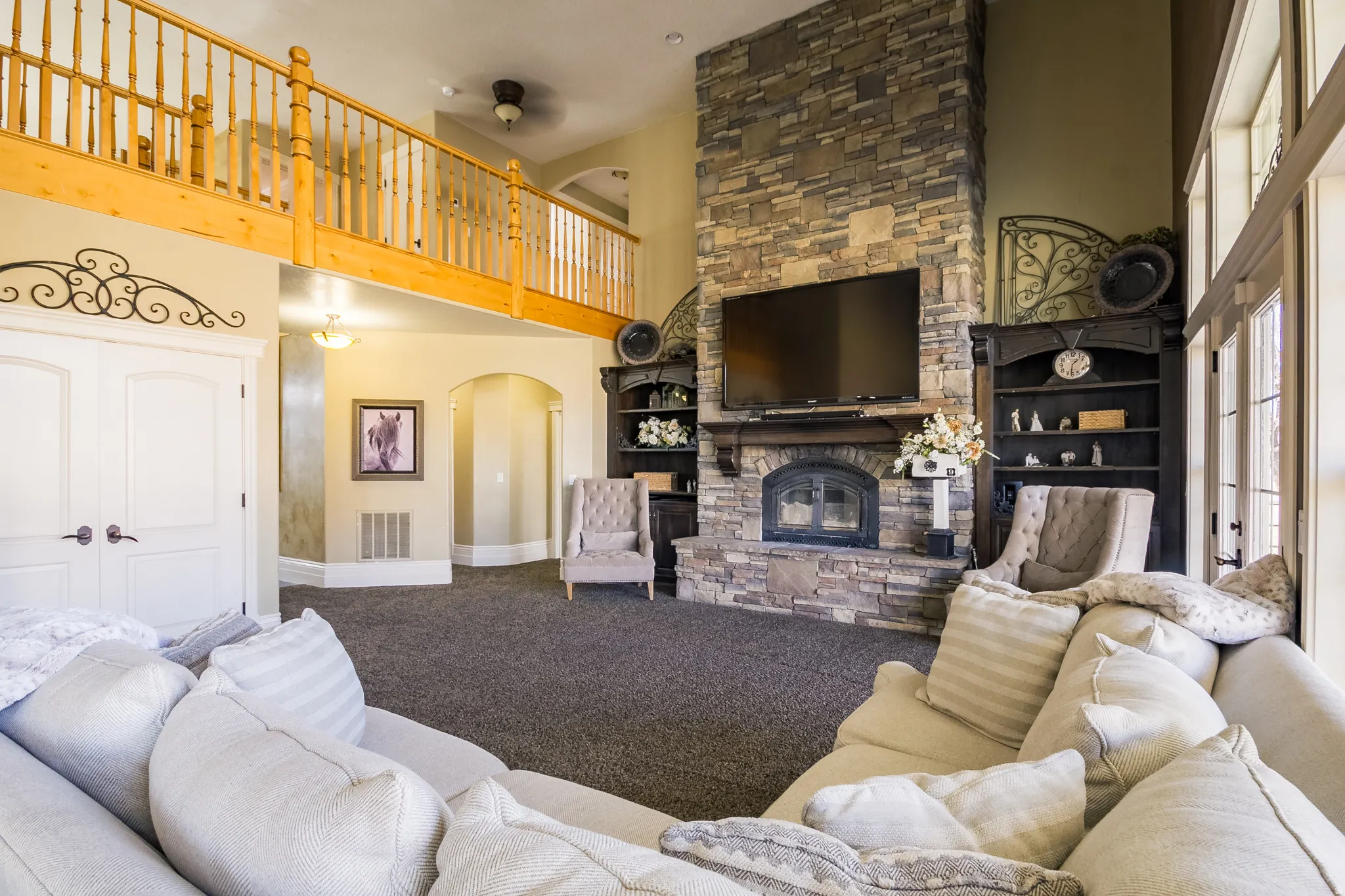 Carpeted living room featuring a high ceiling, arched walkways, a fireplace, and ceiling fan