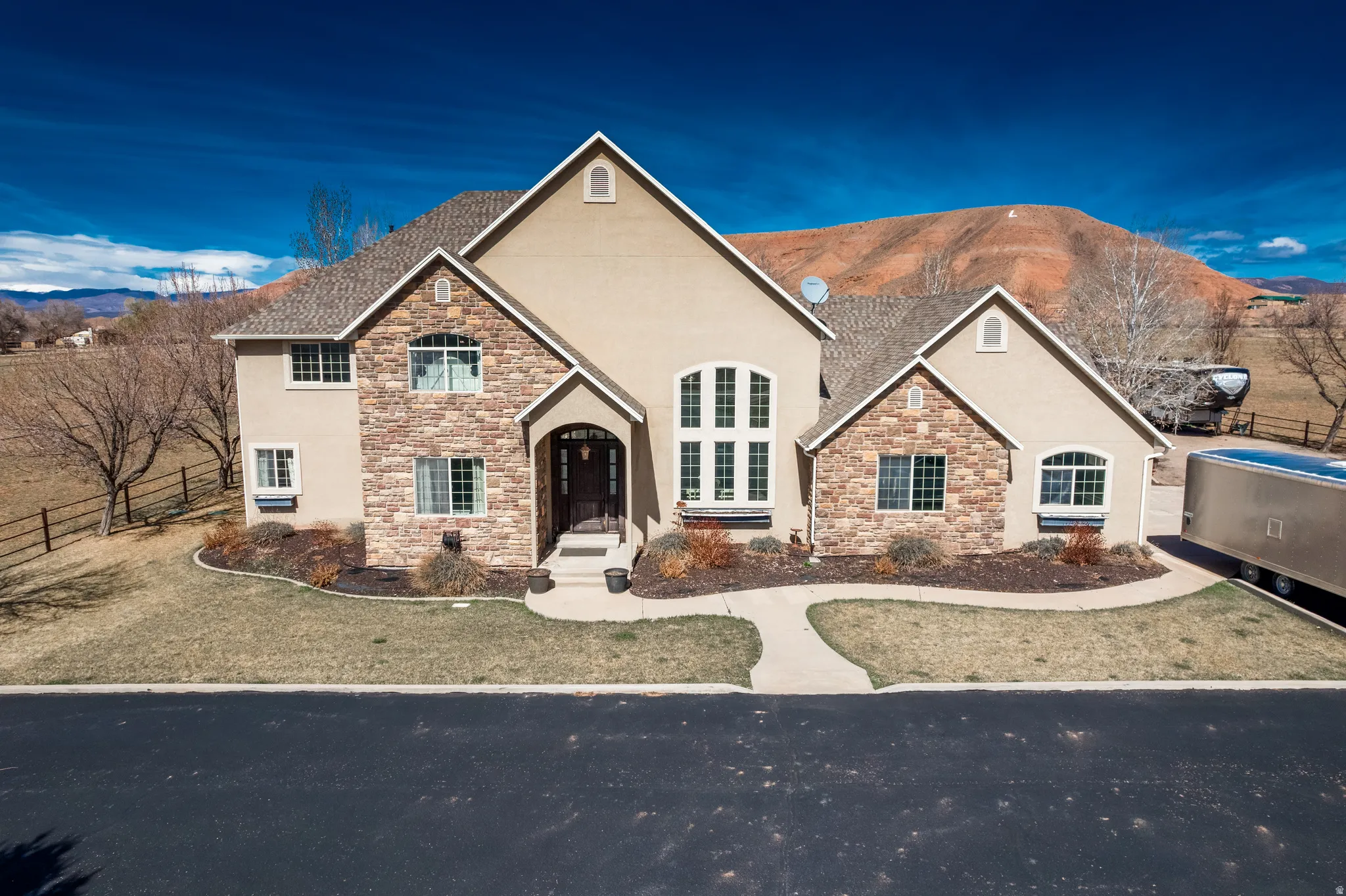 View of front of house featuring a mountain view, stone siding, and stucco siding