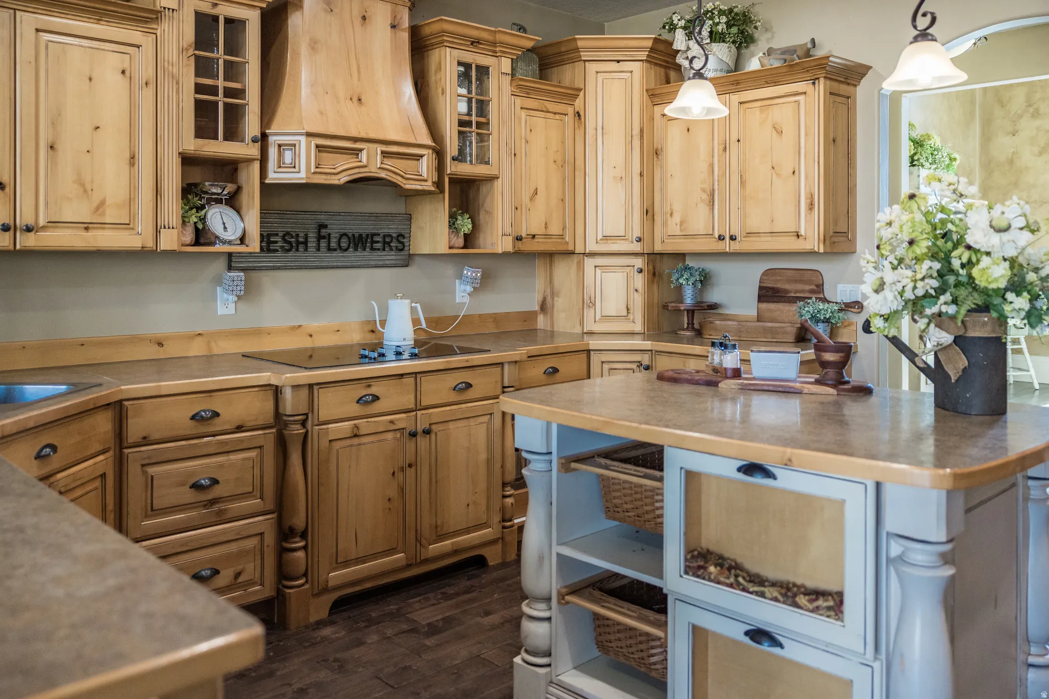 Kitchen featuring open shelves, glass insert cabinets, dark wood-style floors, decorative light fixtures, and dark countertops