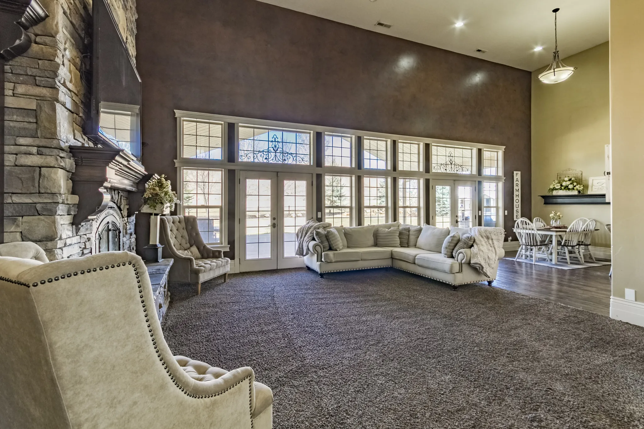 Carpeted living room featuring french doors, a high ceiling, and a stone fireplace