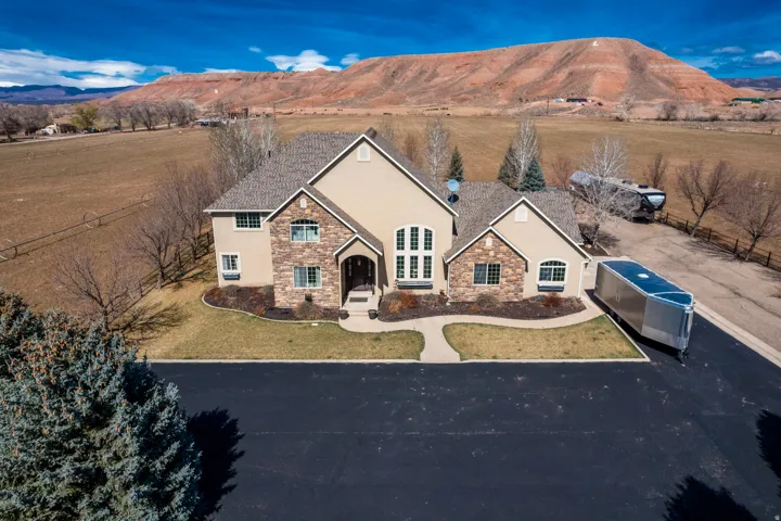 View of front facade featuring stone siding, stucco siding, a mountain view, and a front yard