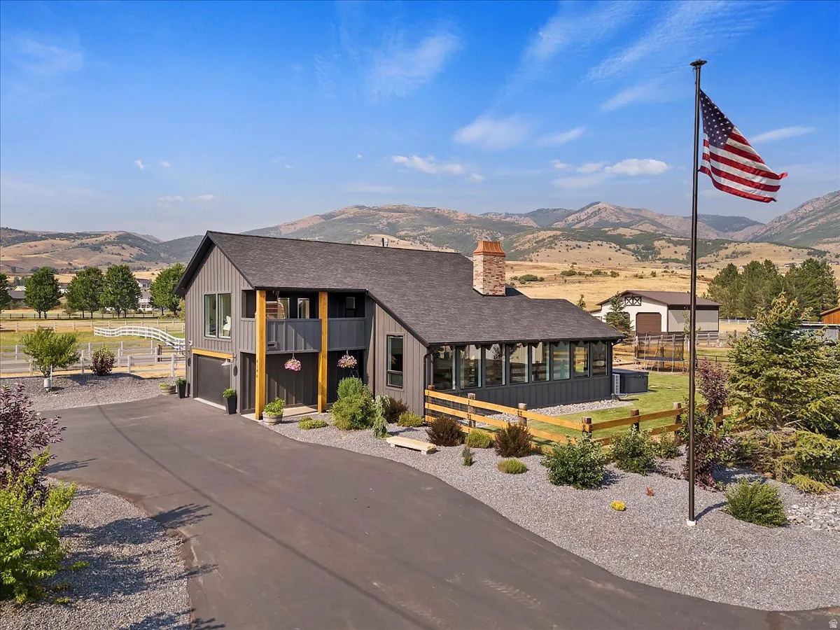View of front of property with a mountain view, a shingled roof, an attached garage, a chimney, and asphalt driveway