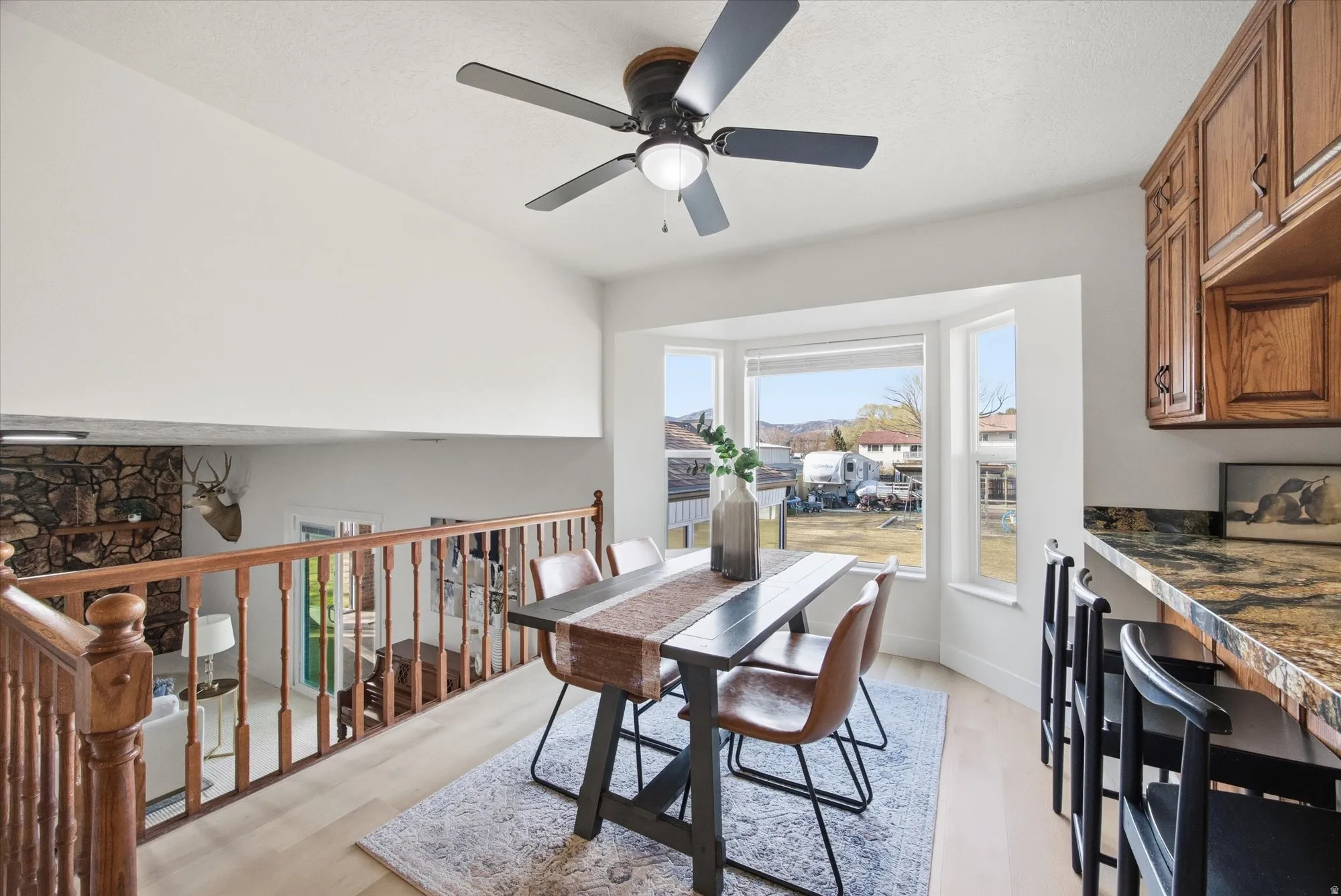 Kitchen with a peninsula, stainless steel electric stove, ceiling fan, oak cabinets, LVP flooring and dark stone counters
