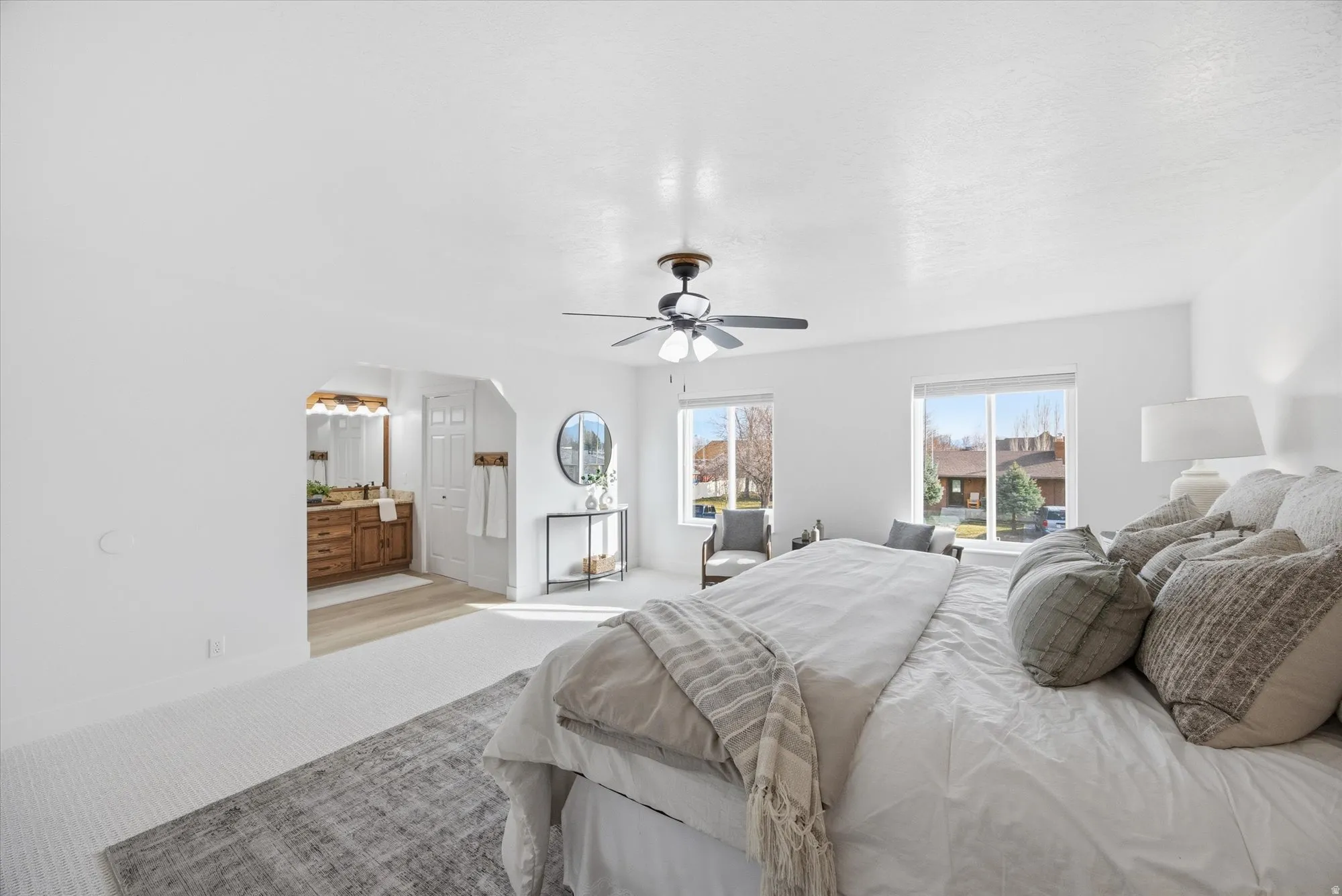 Carpeted bedroom with arched walkways, connected bathroom, and ceiling fan