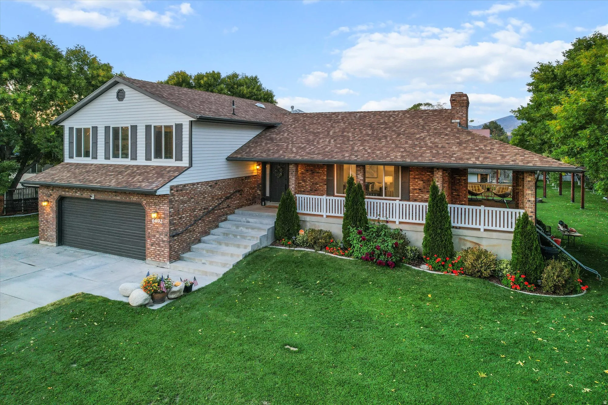 Split level home with an attached garage, brick siding, a front yard, covered porch, and concrete driveway