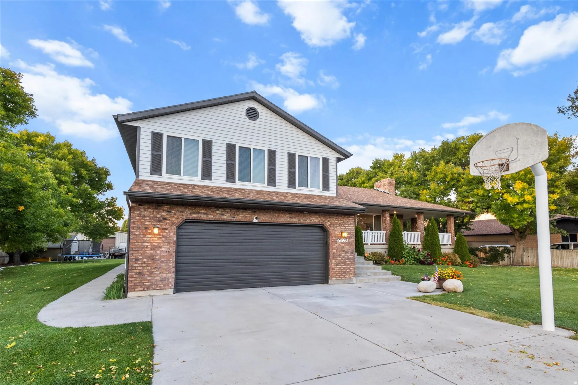 View of front facade featuring a front yard, an attached garage, driveway, brick siding, and a chimney