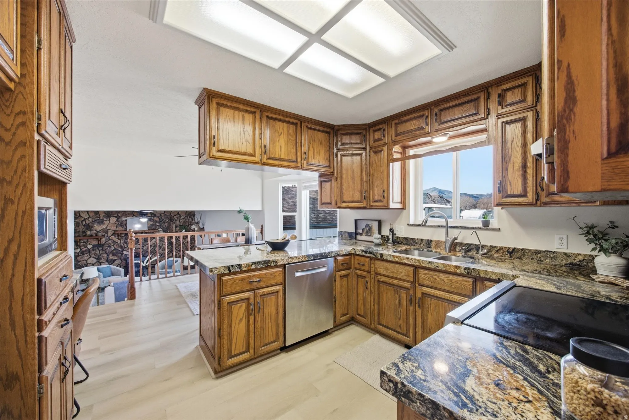 Kitchen featuring wood finish cabinetry, a peninsula, stainless steel appliances, and light LVP floors