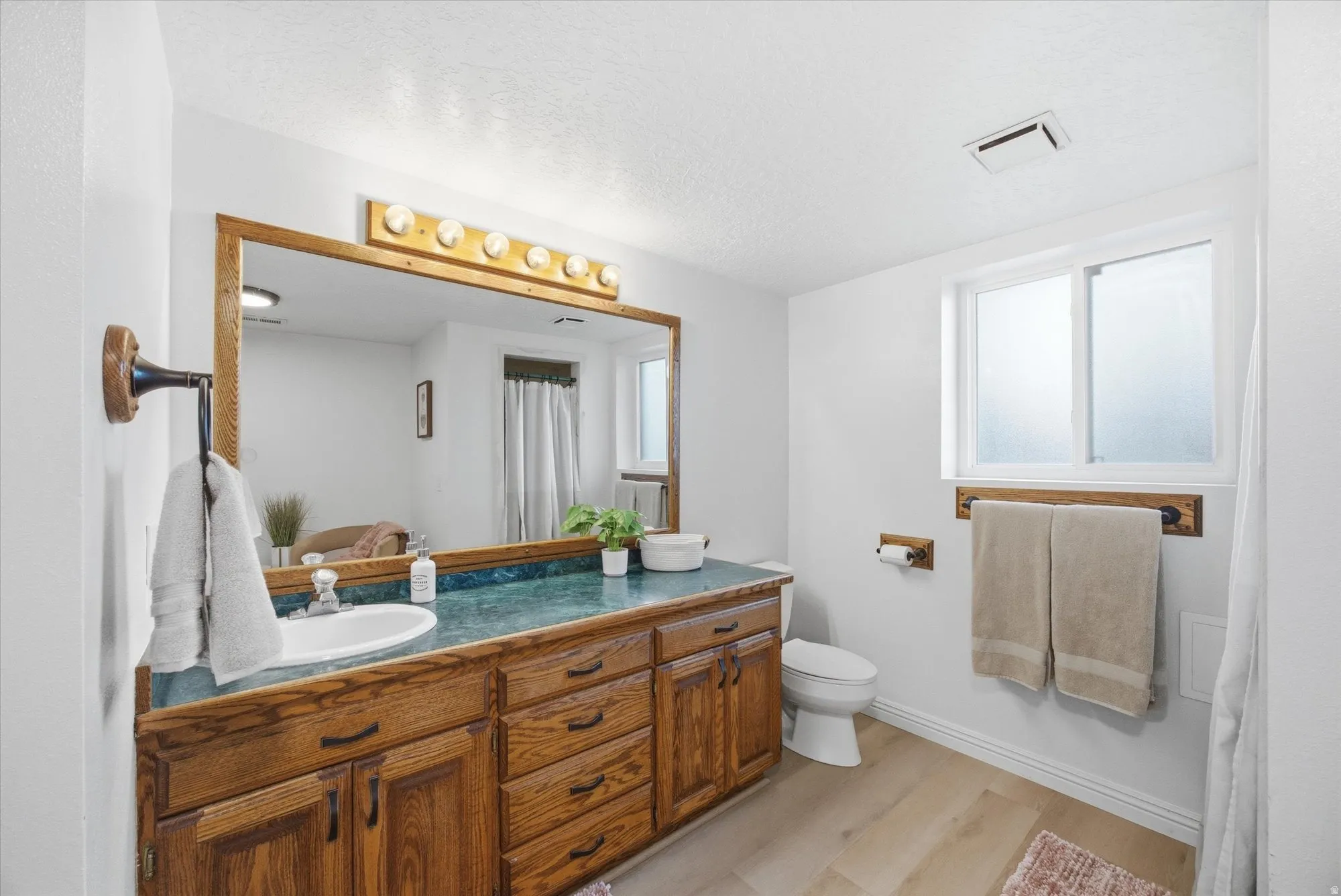 Full bath with vanity, light wood-style floors, a textured ceiling, and a shower with shower curtain