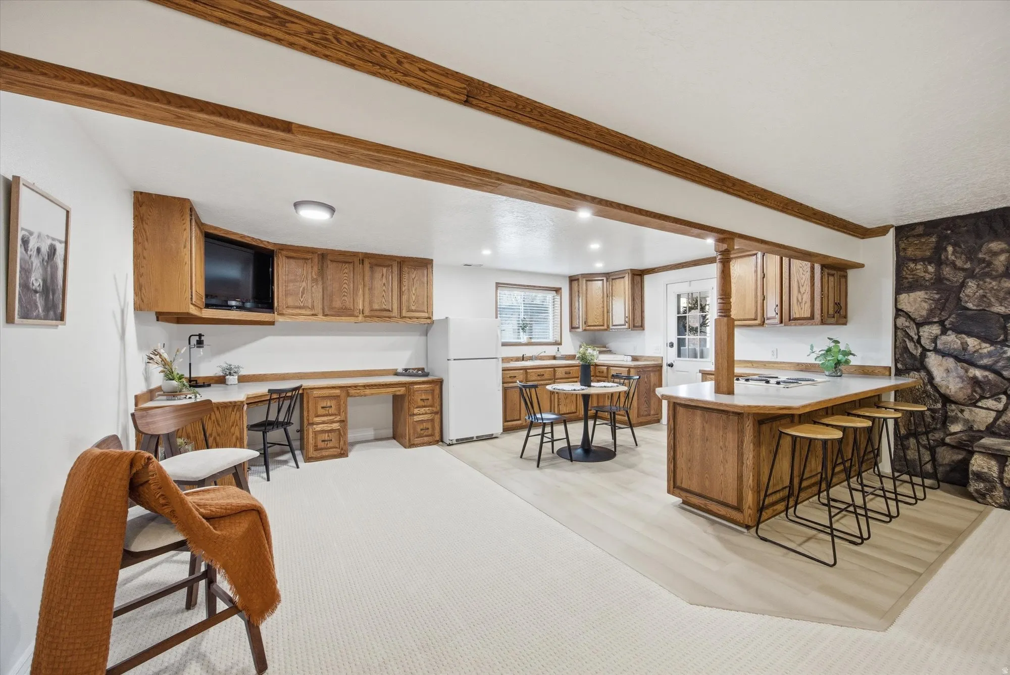 Kitchen featuring wood finish cabinets, a breakfast bar area, a peninsula, built in study area, and freestanding refrigerator