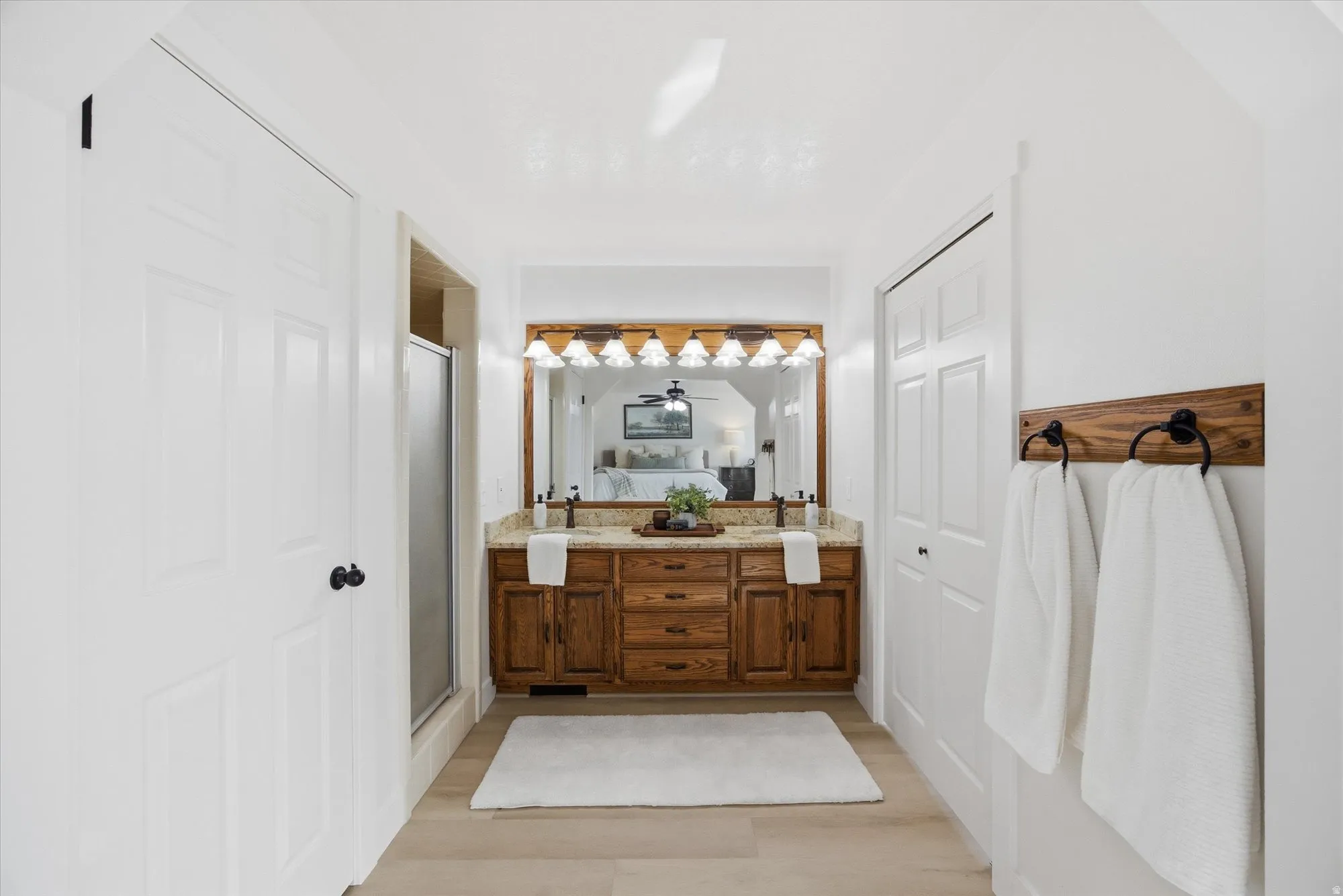 Full bathroom with double vanity, a stall shower, and light LVP flooring