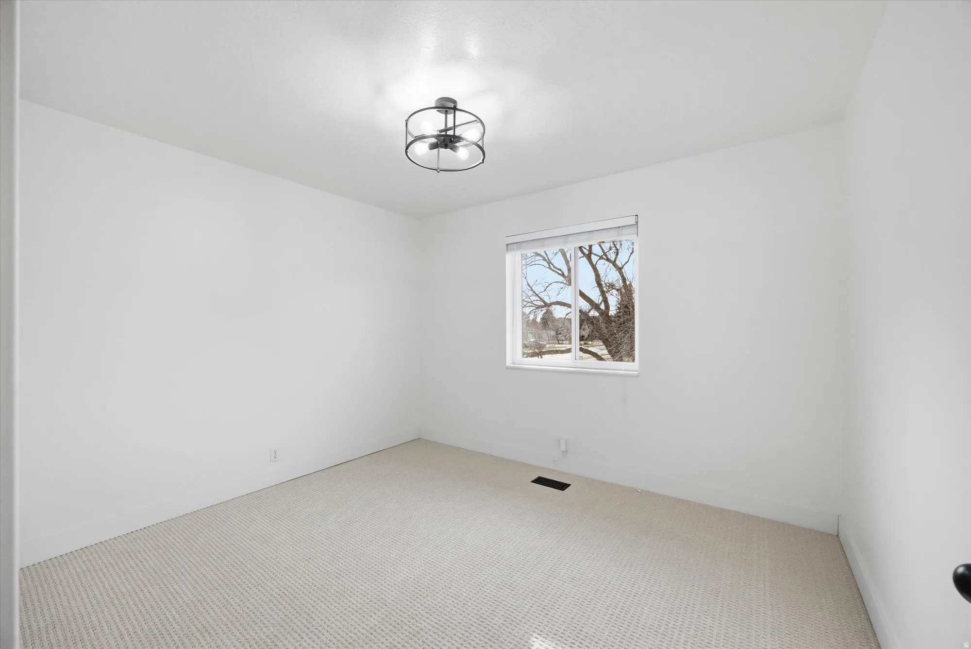 Empty room with light colored carpet and baseboards